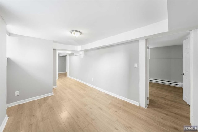 spare room with baseboard heating and light hardwood / wood-style flooring