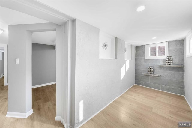 corridor with tile walls and light hardwood / wood-style flooring