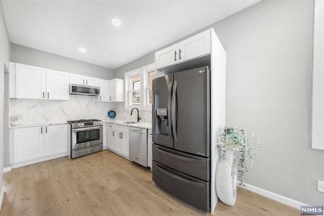 kitchen with light wood-type flooring, stainless steel appliances, white cabinetry, and sink