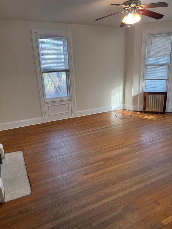 spare room with radiator heating unit, dark hardwood / wood-style floors, and ceiling fan