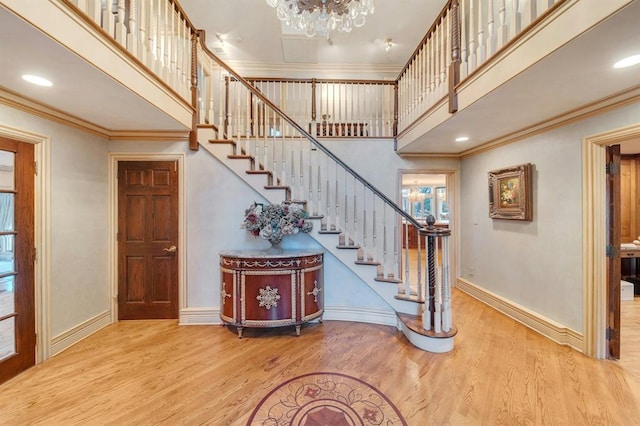 stairs with crown molding, a towering ceiling, and wood-type flooring