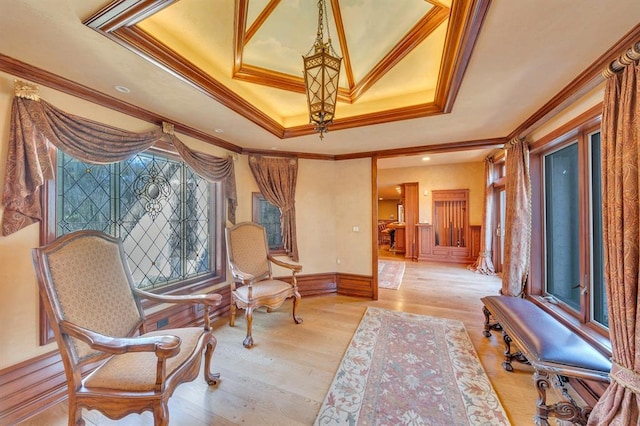 living area featuring a tray ceiling, light hardwood / wood-style floors, and ornamental molding