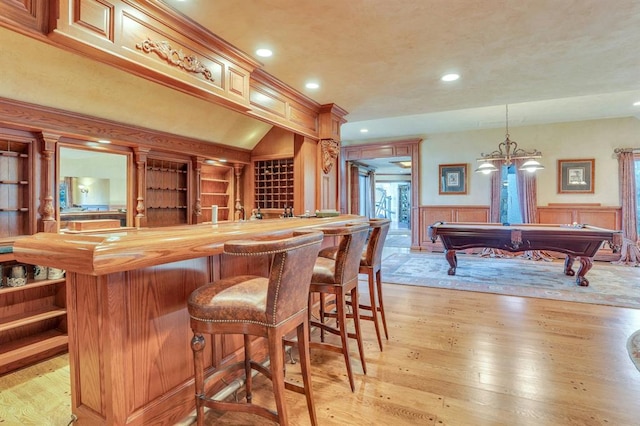 bar featuring wooden counters, built in features, light hardwood / wood-style floors, hanging light fixtures, and pool table