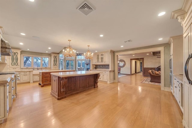 kitchen with decorative backsplash, a center island, pendant lighting, and light wood-type flooring