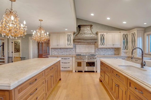 kitchen featuring sink, a center island, light hardwood / wood-style flooring, range with two ovens, and custom exhaust hood