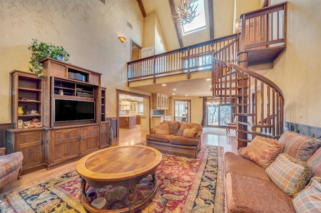 living room with an inviting chandelier, a towering ceiling, and light hardwood / wood-style flooring