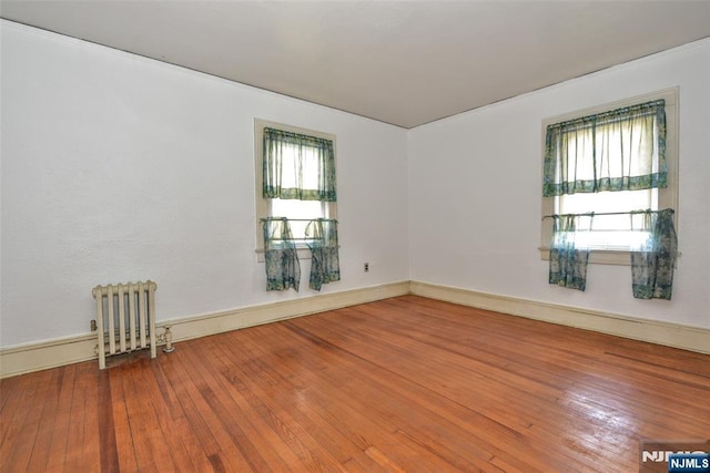 empty room with radiator, hardwood / wood-style flooring, and plenty of natural light