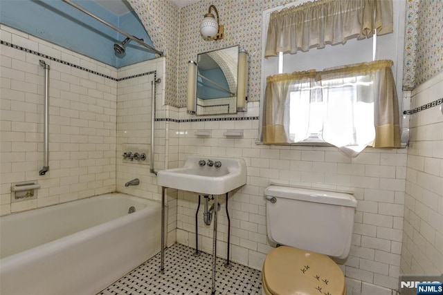 full bathroom featuring tile patterned flooring, sink, toilet, tile walls, and tiled shower / bath