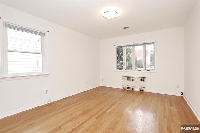 unfurnished room with radiator and light hardwood / wood-style floors