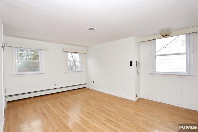 unfurnished room with light hardwood / wood-style floors and a baseboard heating unit