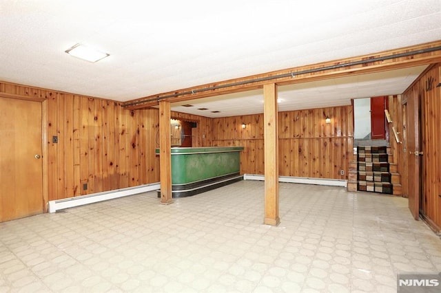 basement featuring wood walls and a baseboard radiator