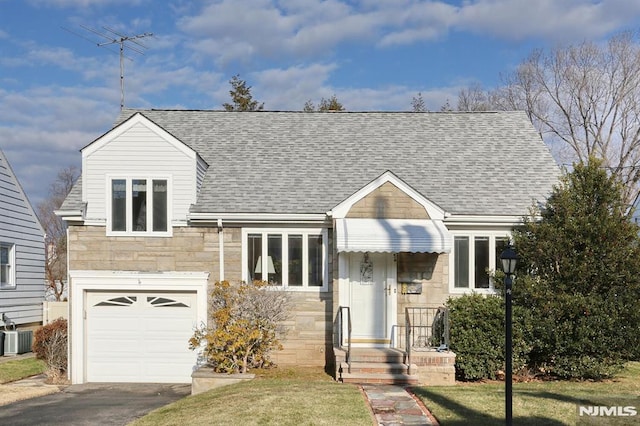 view of front of house with central AC, a front yard, and a garage