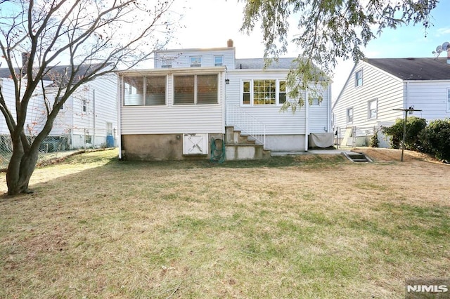 rear view of house with a yard and a sunroom