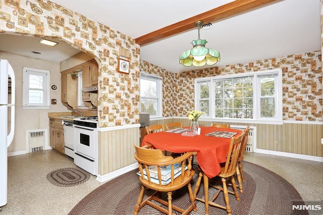 dining space featuring beam ceiling, radiator, and sink