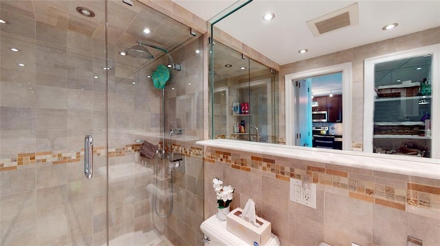 bathroom with tile walls, an enclosed shower, and toilet