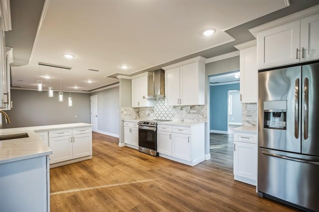 kitchen featuring white cabinetry, wall chimney exhaust hood, hanging light fixtures, stainless steel appliances, and light hardwood / wood-style flooring