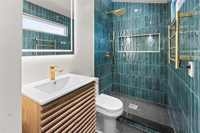 bathroom featuring tile patterned flooring, vanity, toilet, and a tile shower