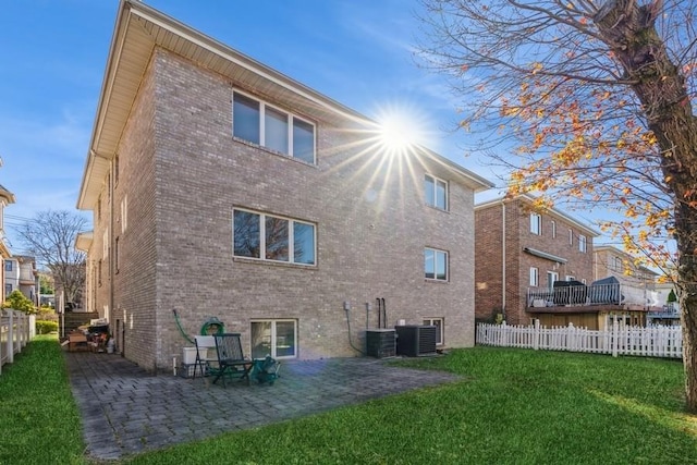 back of property with central AC unit, a yard, and a patio