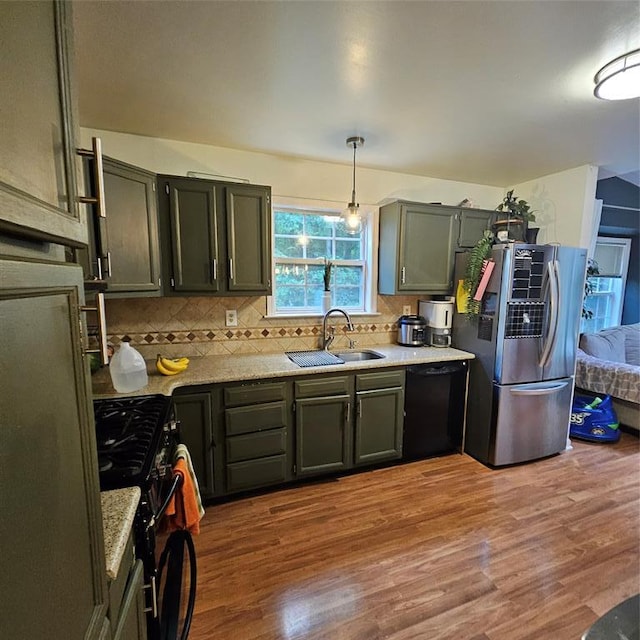 kitchen with sink, hanging light fixtures, wood-type flooring, decorative backsplash, and black appliances