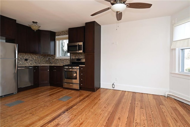 kitchen with stainless steel appliances, a healthy amount of sunlight, and light hardwood / wood-style floors