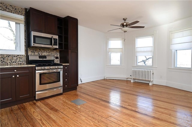 kitchen featuring dark brown cabinetry, a wealth of natural light, radiator heating unit, and stainless steel appliances