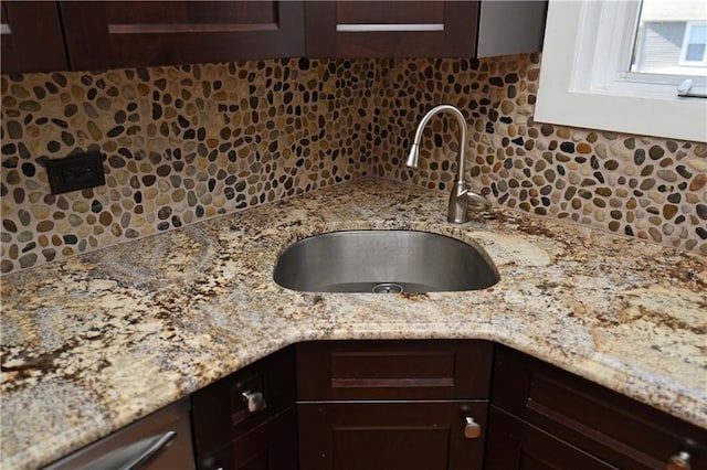 room details featuring light stone counters, dark brown cabinetry, and sink