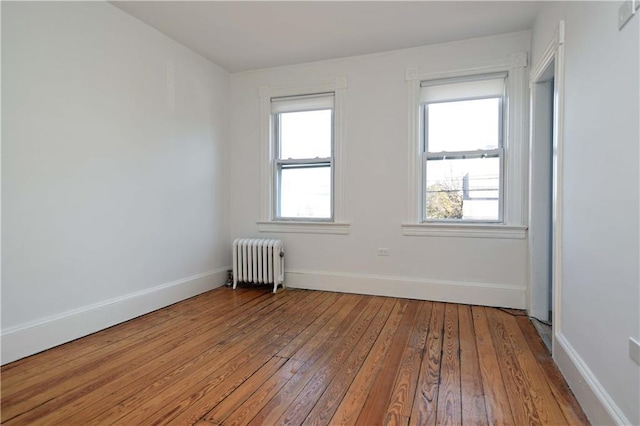 spare room featuring radiator and wood-type flooring