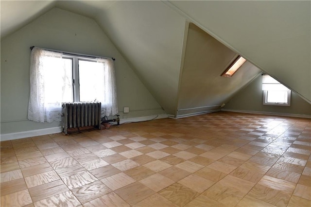 additional living space featuring radiator and vaulted ceiling with skylight