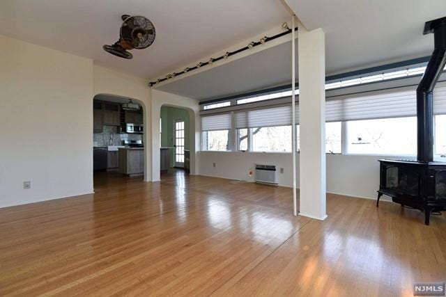 unfurnished living room featuring wood-type flooring and a wood stove