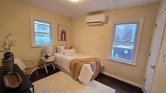 bedroom with a wall mounted AC and dark hardwood / wood-style floors