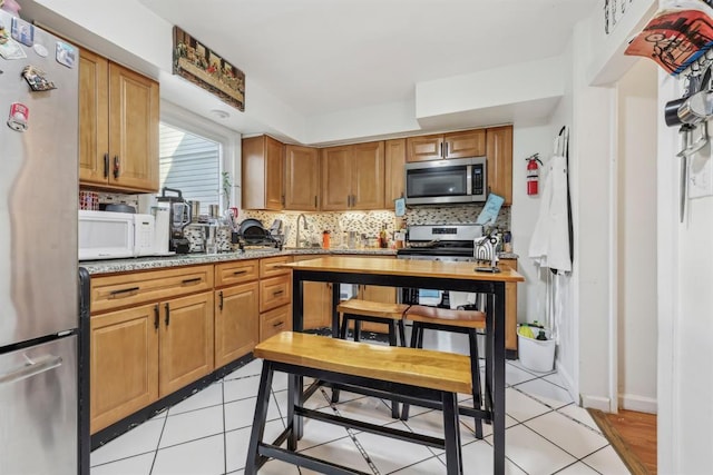 kitchen featuring light stone counters, light tile patterned floors, backsplash, and appliances with stainless steel finishes