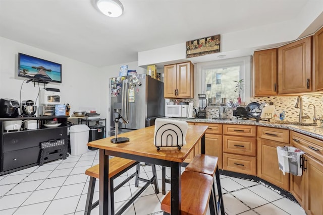 kitchen with light stone countertops, sink, light tile patterned floors, and tasteful backsplash