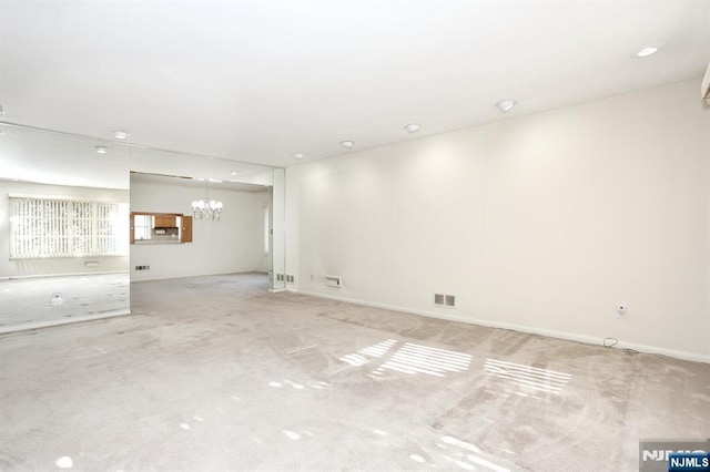 carpeted spare room with a notable chandelier