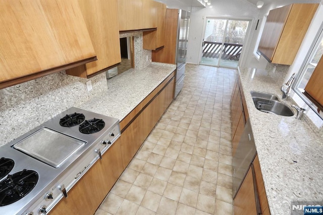 kitchen featuring sink, light stone counters, a fireplace, stainless steel gas cooktop, and light tile patterned flooring