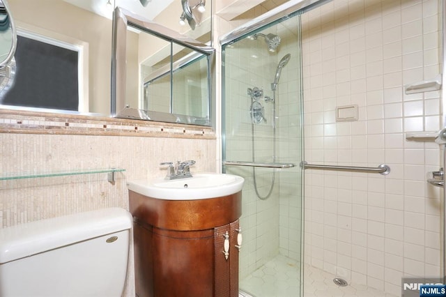 bathroom featuring vanity, toilet, tile walls, and a shower with shower door