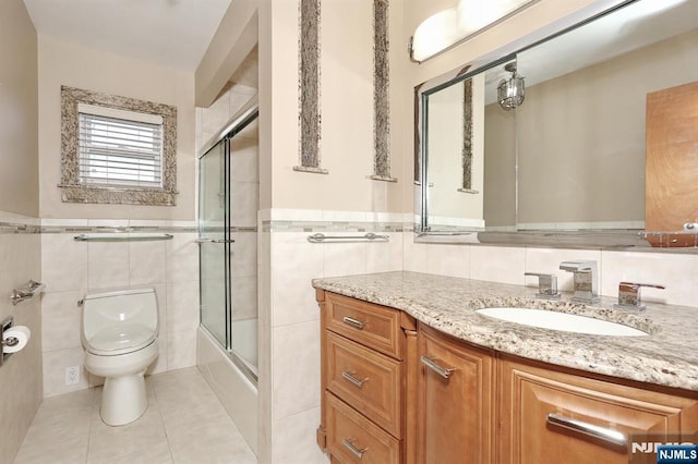 full bathroom with enclosed tub / shower combo, tile walls, vanity, tile patterned floors, and toilet