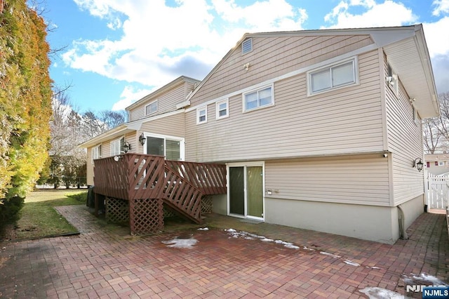 back of house featuring a wooden deck and a patio