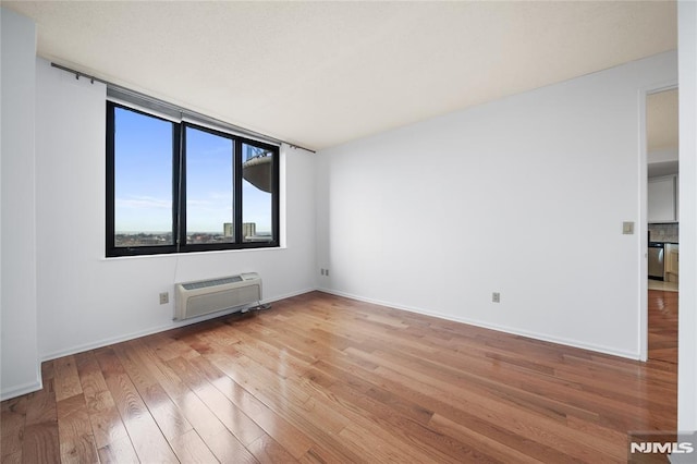 spare room with light hardwood / wood-style floors and a wall mounted AC