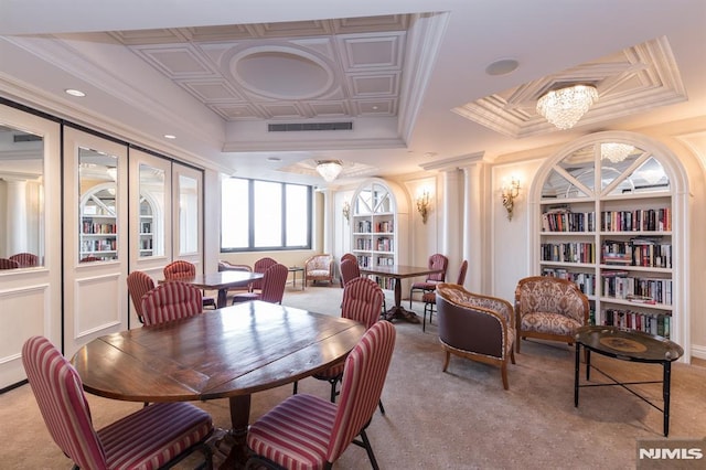 carpeted dining area featuring french doors, built in features, a notable chandelier, decorative columns, and ornamental molding