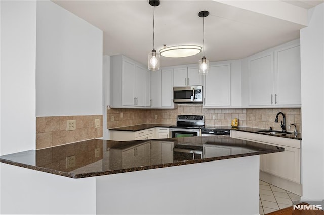 kitchen featuring kitchen peninsula, stainless steel appliances, sink, light tile patterned floors, and white cabinetry