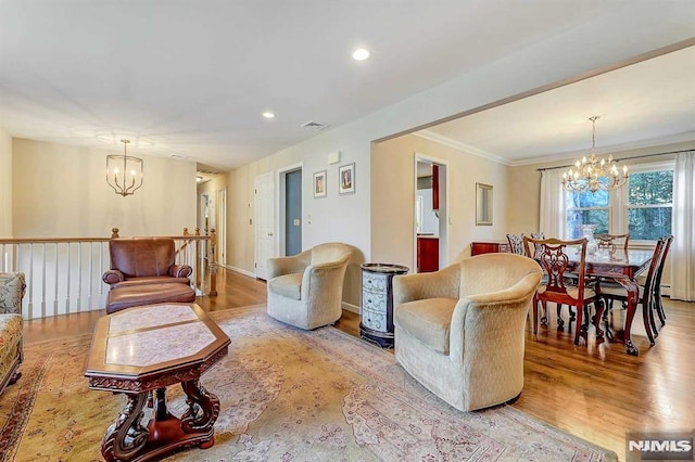 living room with ornamental molding, a notable chandelier, and light hardwood / wood-style flooring