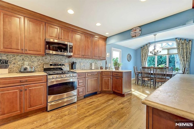 kitchen with stainless steel appliances, light wood-type flooring, an inviting chandelier, decorative light fixtures, and tasteful backsplash