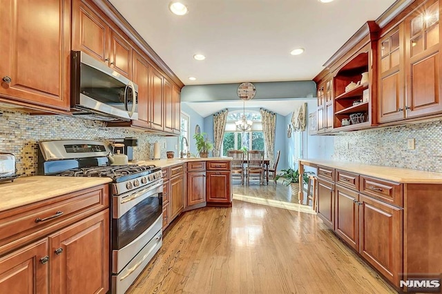 kitchen with light hardwood / wood-style flooring, a chandelier, decorative light fixtures, tasteful backsplash, and appliances with stainless steel finishes