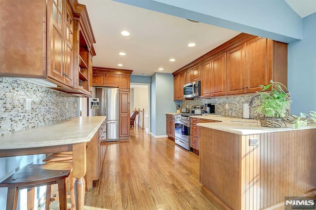 kitchen with stainless steel appliances, light hardwood / wood-style flooring, vaulted ceiling, and decorative backsplash