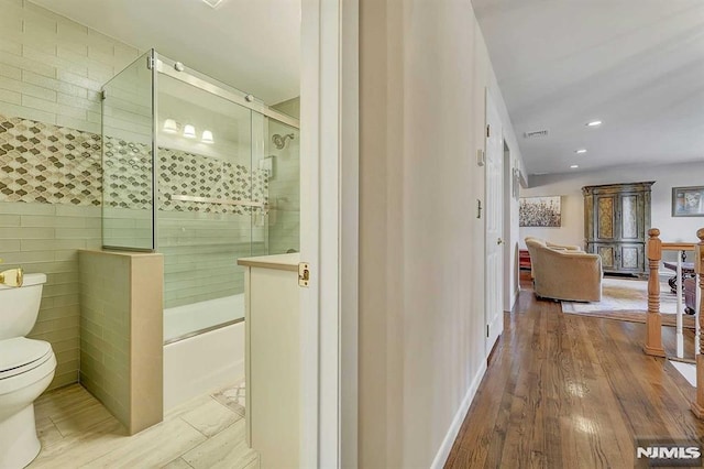 bathroom featuring a shower with door, toilet, and hardwood / wood-style flooring