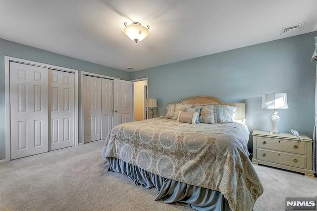 bedroom featuring multiple closets and light carpet