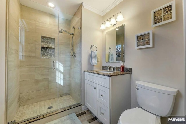 bathroom featuring toilet, a shower with door, crown molding, and vanity