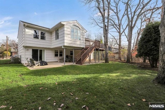 back of property featuring a deck, a patio area, and a lawn