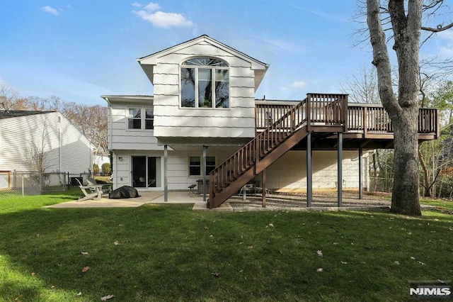 rear view of property featuring a patio, a yard, and a wooden deck