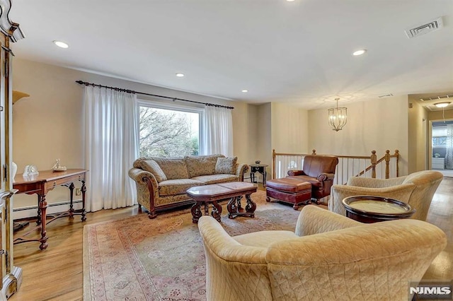 living room with a notable chandelier, light hardwood / wood-style flooring, and a baseboard radiator